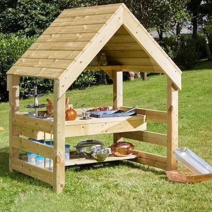 Wooden mud kitchen under a pitched boarded roof, with a tap, metal bowl and slatted lower shelf.
