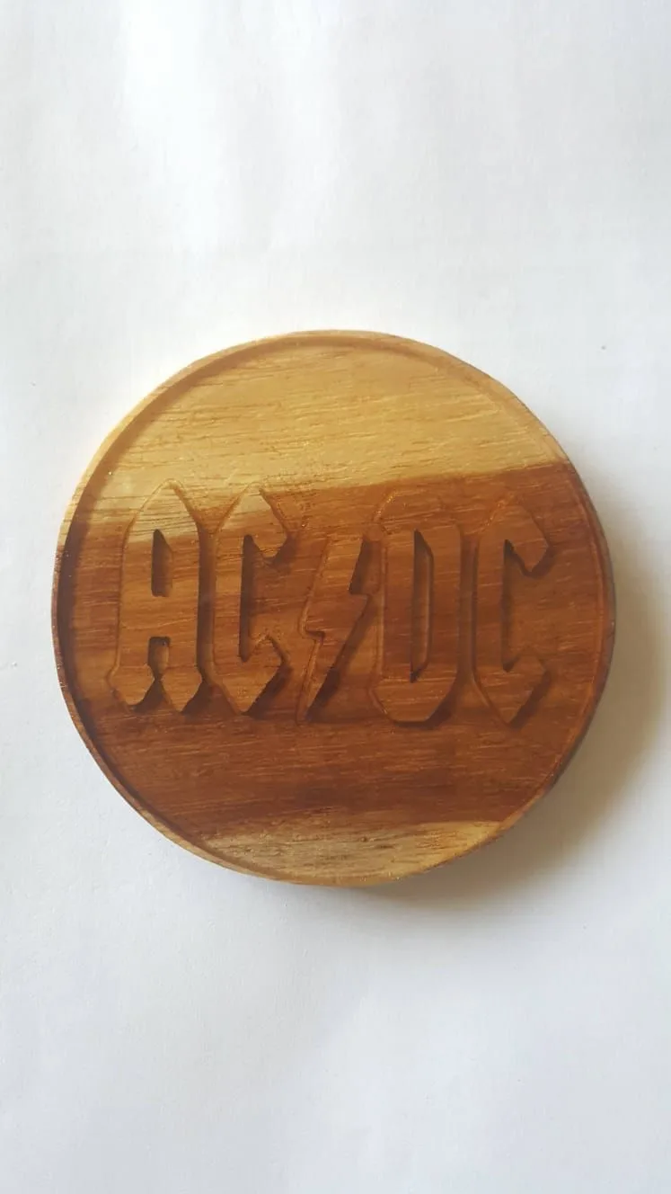 Round wooden coaster with a raised rim and the AC/DC logo carved into its face.