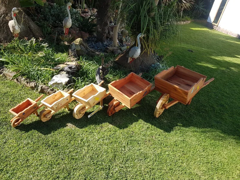 Five wooden wheelbarrow planters in graduated sizes, each with round timber wheels and two handles.