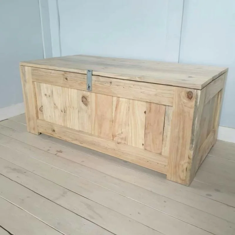 Wooden toy chest with a hinged overhanging lid, metal hasp at the front and framed side panels.