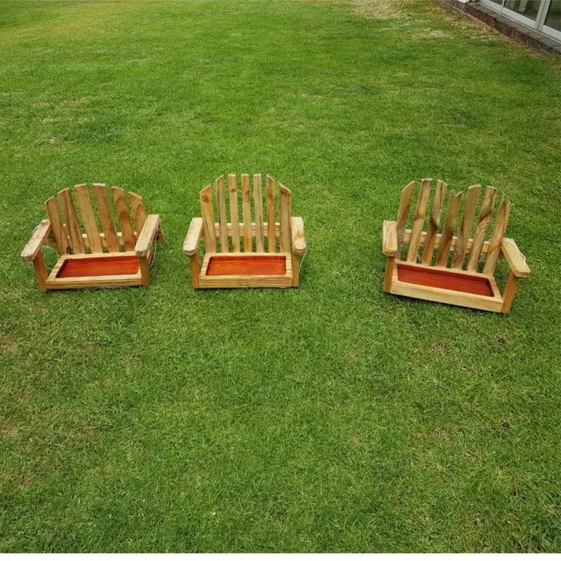 Three small wooden Adirondack-style bird feeder benches with slatted backs and wide armrests, standing on grass.