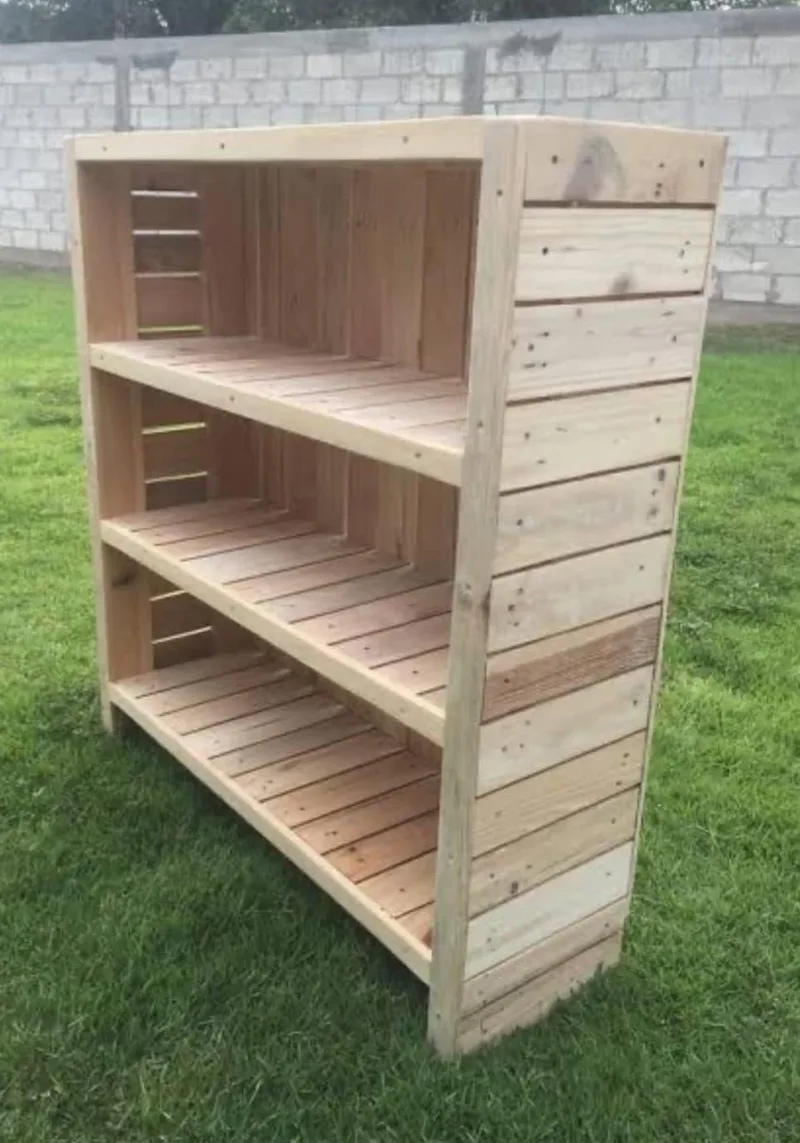 Open three-tier wooden shelf unit with slatted shelves and plank-clad sides, standing on grass.